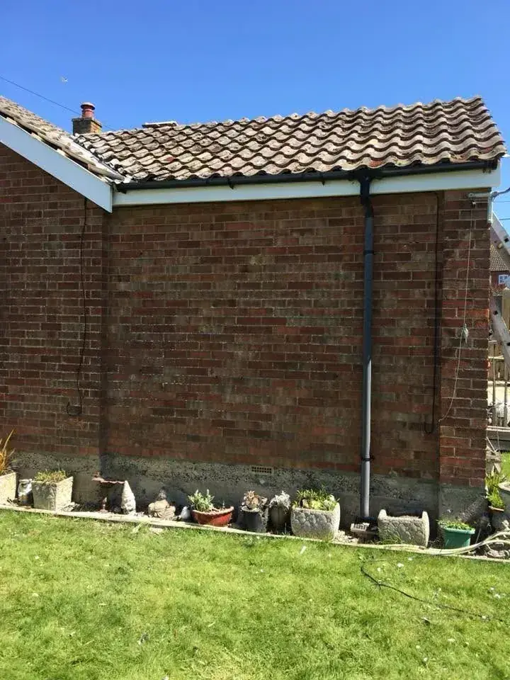 New black guttering and downpipe fitted to a red brick gable end in Norwich