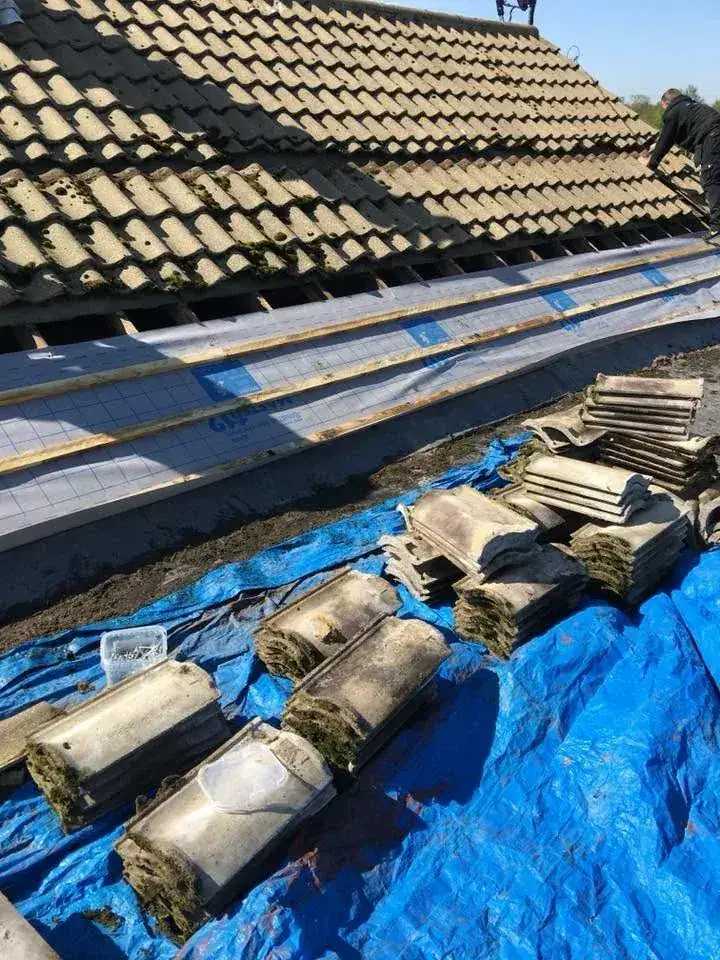 Re-roof in progress with the old tiles stacked and battens exposed in Norwich