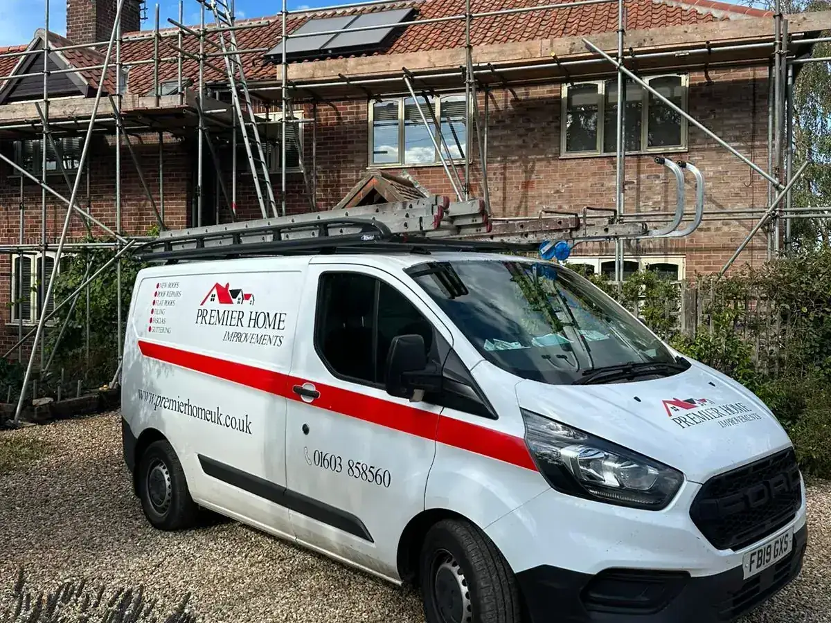 Branded van on a driveway beside a scaffolded house with solar panels in Norfolk