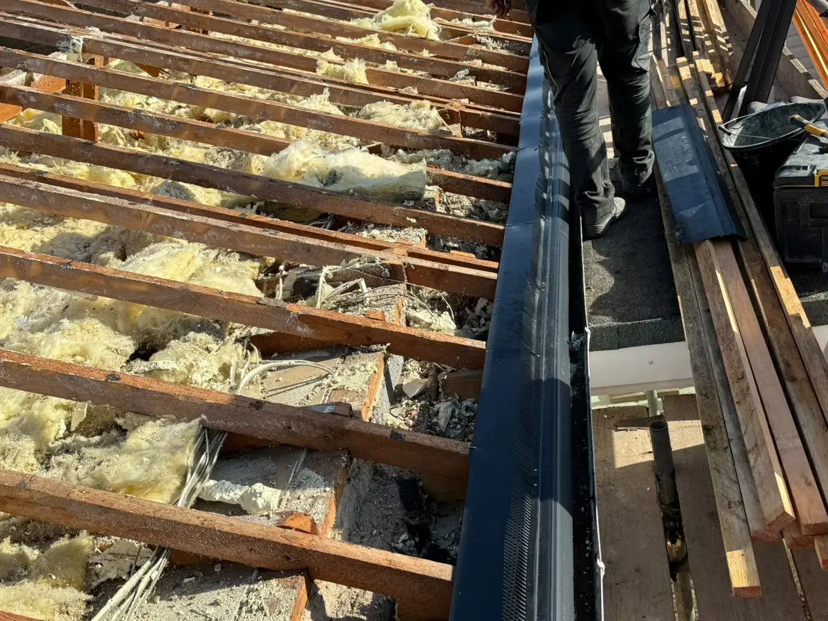 Close view of exposed rafters and loft insulation after the roof covering was removed