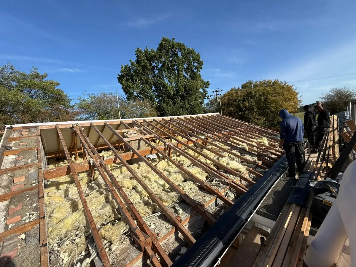 Roofers on a bungalow roof stripped to bare rafters in Diss