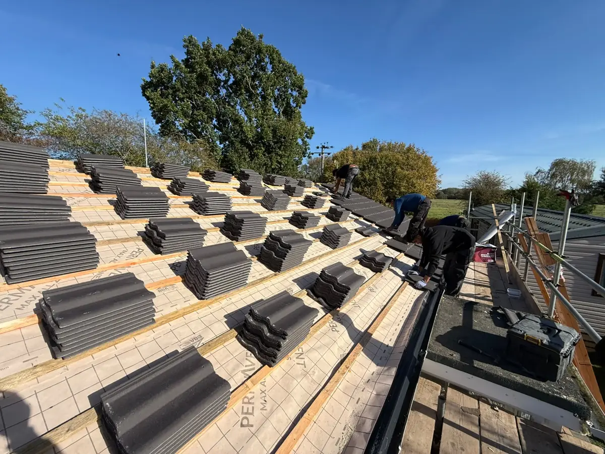 Roofers laying new grey concrete tiles on a bungalow in Diss