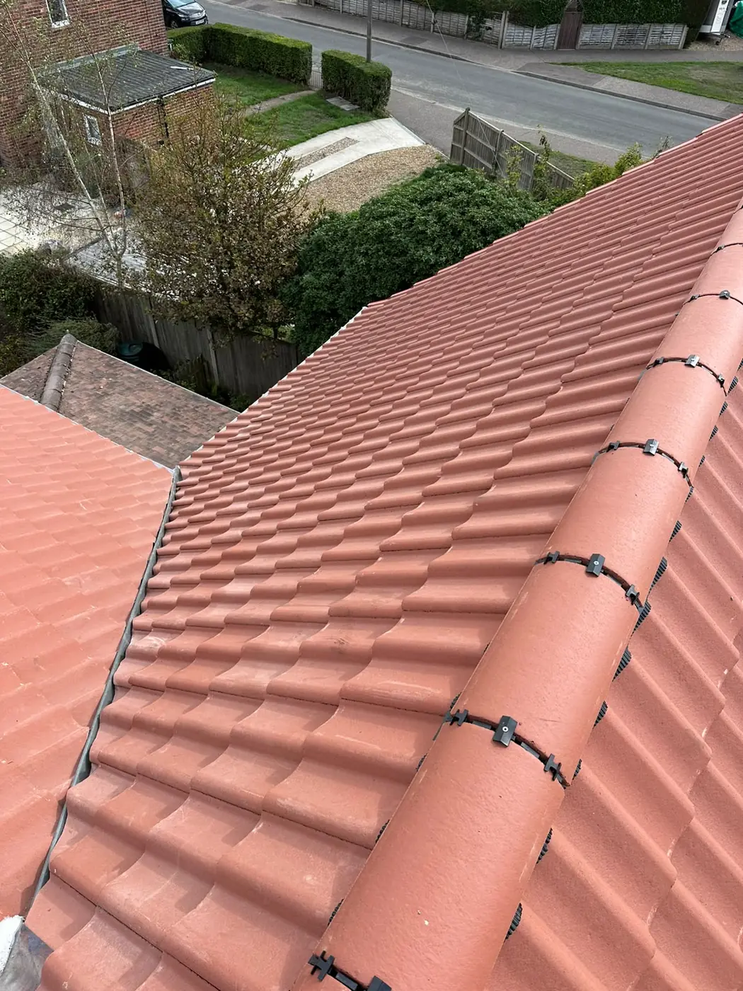 Looking down a new pantile slope and hip towards a garden and road in Holt