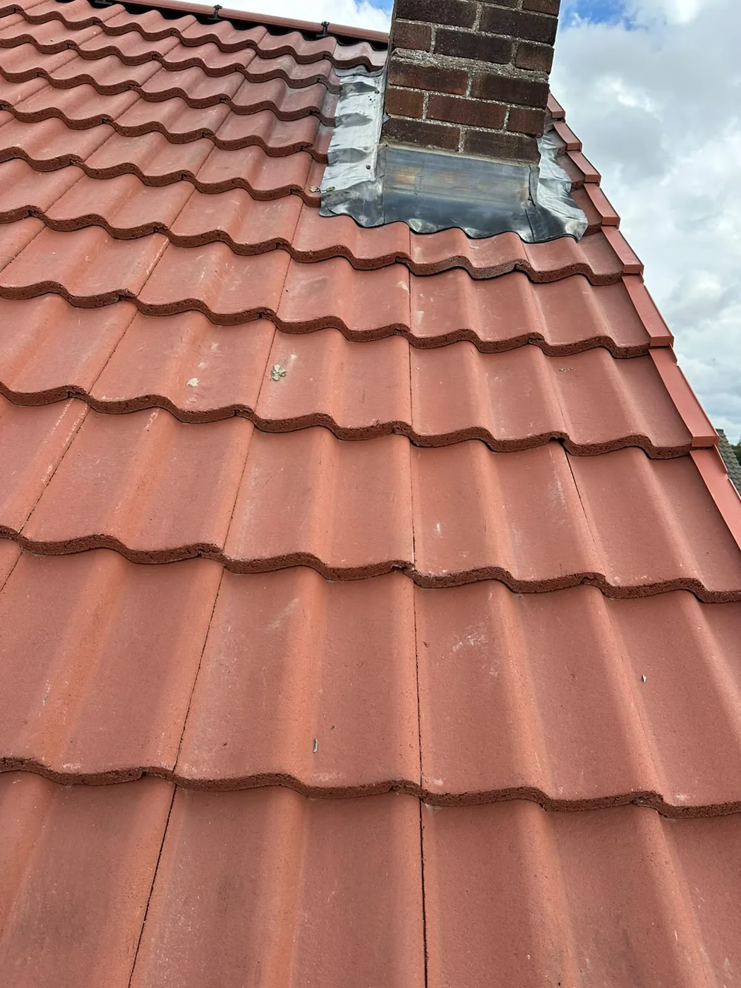 Fresh lead soakers and flashing to a chimney with red dry verge in Holt
