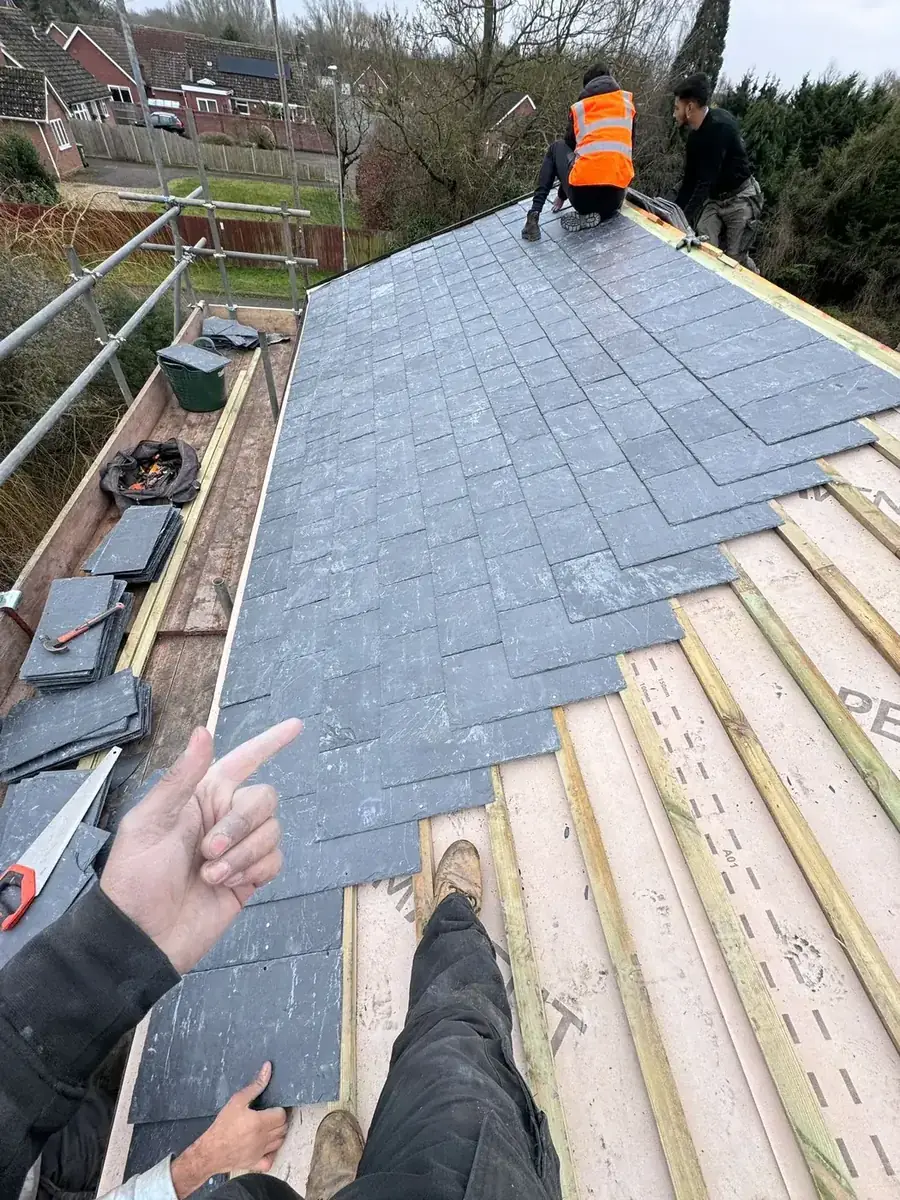Roofer laying natural slates over new battens and underfelt on a Norfolk re-roof