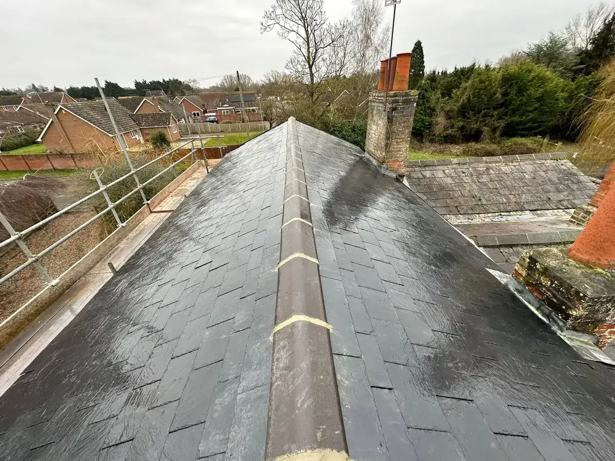 Finished natural slate roof with a bedded clay ridge and brick chimney