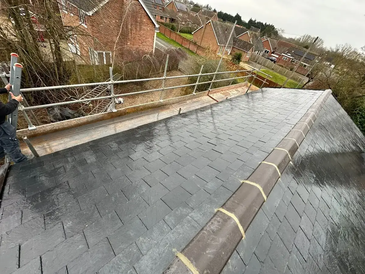 Roofer working on a newly slated roof with a bedded ridge