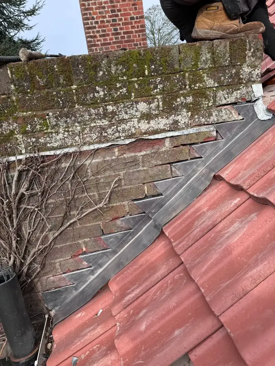 New terracotta pantiles and stepped lead flashing against a stone parapet wall