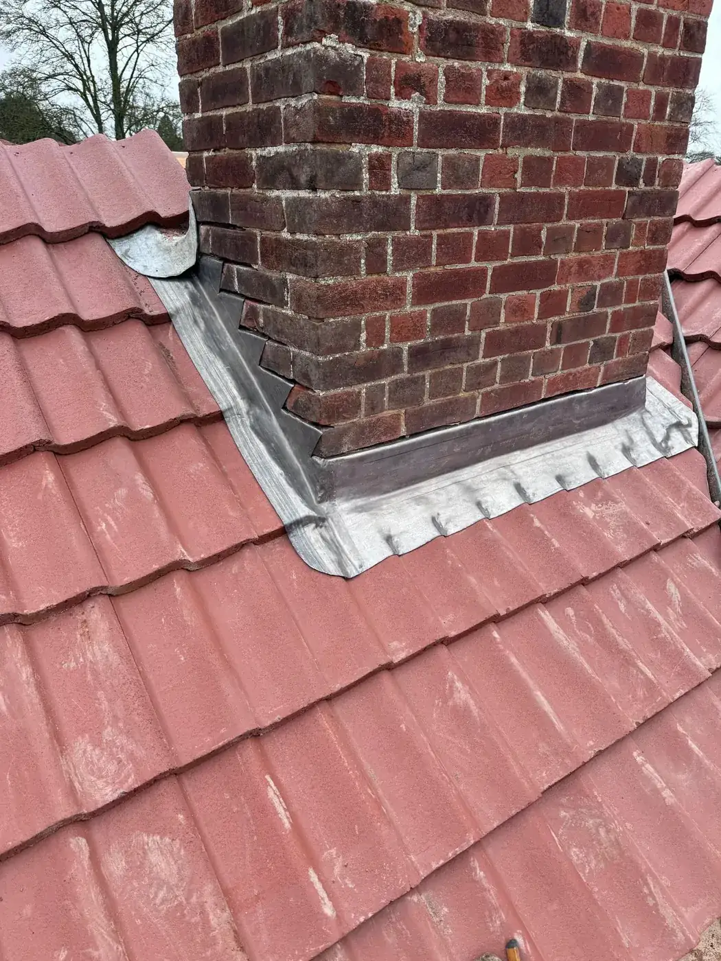 Fresh lead flashing and apron around a brick chimney stack on a new pantile roof